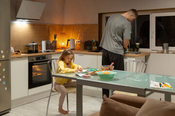 Father and daughter cooking and drawing in kitchen
