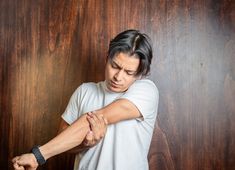 Fototapeta premium Man with elbow pain highlighted in red. Young man with elbow pain due to arthritis
