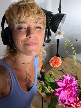 Artist poses with flowers in a bright studio setting