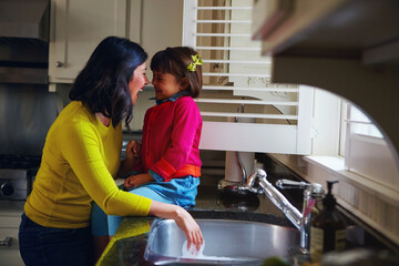 Bonding, mother and child with laugh at kitchen sink for fun chores, washing dishes and nose touch....