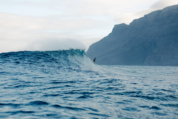 Skilled surfer carving along towering wave during an intense training