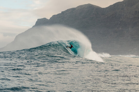 Remote perspective of skilled surfer moving across massive rising wave