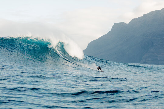 Panoramic seascape showing a huge wave with a surfer in the distance