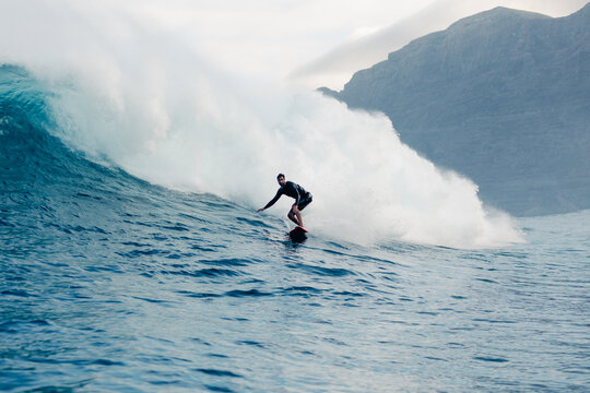 Surfer gliding across a massive wave near Lanzarote&rsquo;s coastline