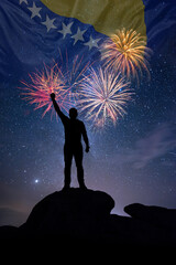 Fototapeta premium Man against background of a fireworks and national flag of Bosnia Herzegovina