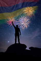 Man against background of a fireworks and national flag of Mauritius