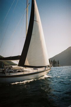 Sailboat gliding on blue sea near mountains
