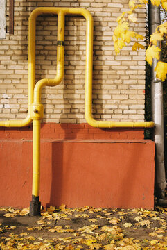 Yellow gas pipe on brick wall in autumn
