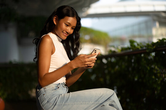 Woman Sitting Outdoors Using Smartphone During Sunset