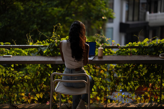 Woman Working on Laptop on Balcony With Greenery 