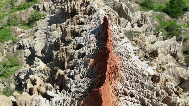 Cinematic top-down perspective of the eroded geological formations at the Viewpoint of the Moon, Luanda Province, Angola, Africa, highlighting the intense orange soil.