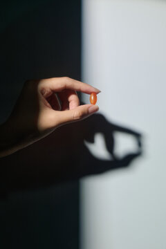 A hand delicately holding a transparent omega-3 capsule
