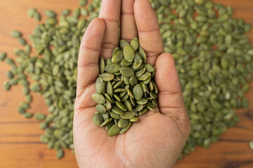 Green Pumpkin seeds are placed on a hand.