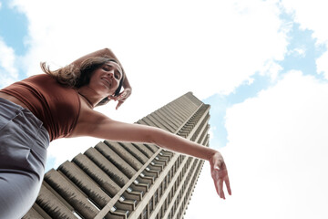 Young dancer performing in front of a skyscraper under cloudy sky