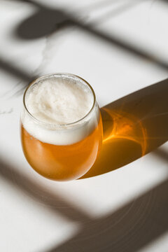 Golden non-alcoholic Beer in Clear Glass on White Surface.