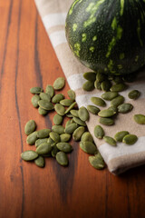 Green Pumpkin seeds, along with a baby pumpkin, placed on a textured background.