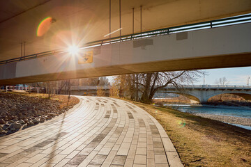 Sunlit Riverside Path Under Bridge in Calgary Downtown