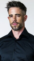 Handsome man with stylish haircut wearing a black shirt poses confidently against a neutral background, showcasing modern fashion and personal style in a portrait