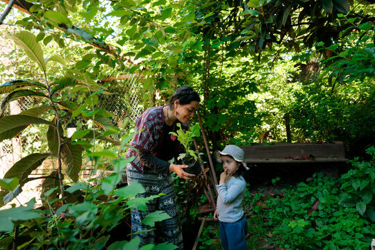 Mother Showing Seedling to Curious Child Daughter 