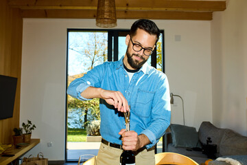 Handsome man opens a bottle of wine at home