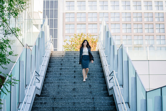 Japanese businesswoman walking down modern city stairs