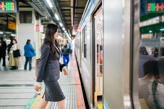 Businesswoman commuting on subway platform boarding train