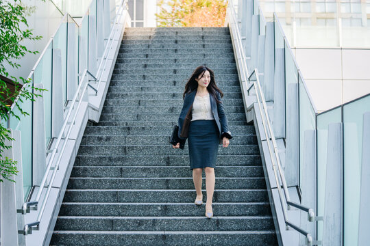 Japanese businesswoman walking down modern urban stairs