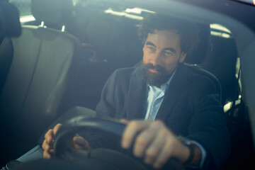 Man driving a car on a sunny day while focusing on the road ahead