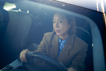 Woman driving a car with focus on the road and a professional outfit