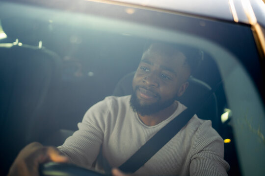 Man enjoying a car ride while fastening his seatbelt and smiling