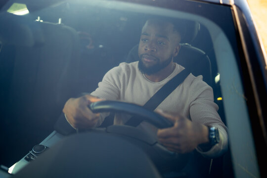 Man enjoying a car ride while fastening his seatbelt and smiling