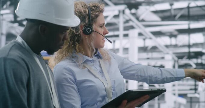 Technical Team Performing on Site Inspection in Modern Automated Factory. Female Manager Uses Tablet Review Digital Schematics While Guiding Male Engineer. Mobile Technology Integration in Industrial