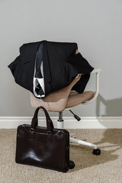 Business suit on office chair with leather briefcase on floor