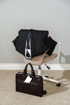 Business suit on office chair with leather briefcase and smartphone