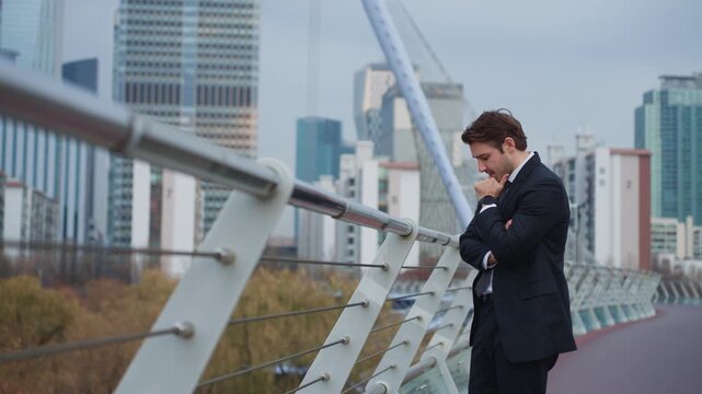 Professional man in suit standing on modern pedestrian bridge pondering business ideas and pointing finger with realization in urban Seoul city background