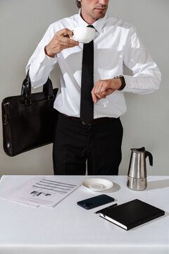 Man in formal outfit drinking coffee and checking time