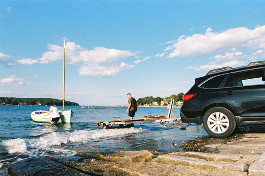 Two men haul out a boat onto a car trailer