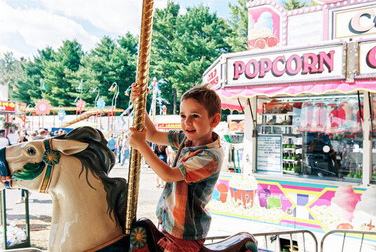 Child Holds on to a carousel horse ride at an amusement park