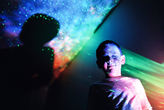 Child stands with eyes closed against celestial background