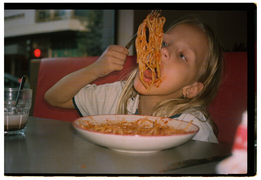 Eight year old girl eating spaghetti in diner booth