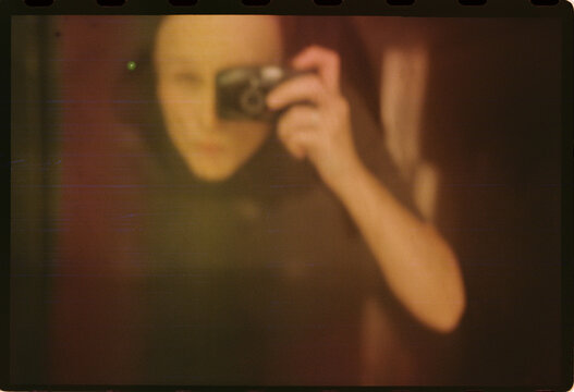 Blurred self portrait with handheld film camera in dim light