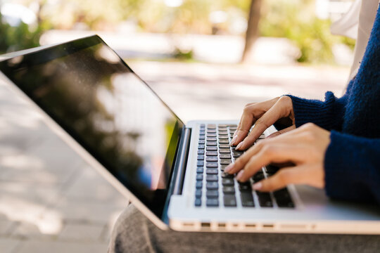 Woman typing on laptop working outdoors