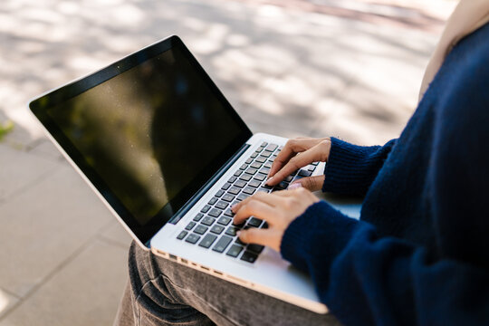 Woman typing on laptop keyboard working outdoors