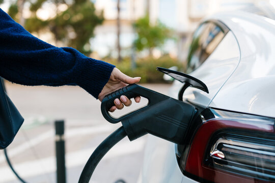 Woman plugging electric car charging cable