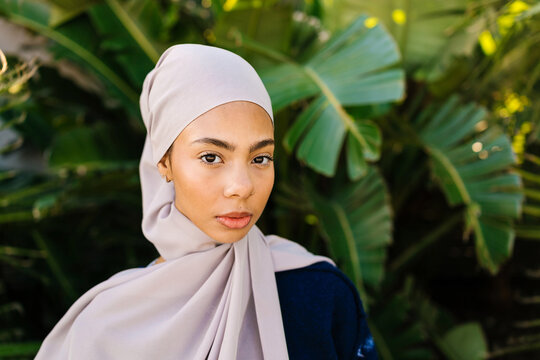 Muslim woman wearing hijab posing with tropical foliage