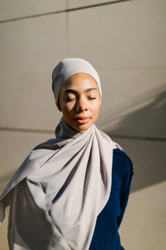Young woman wearing hijab with eyes closed meditating