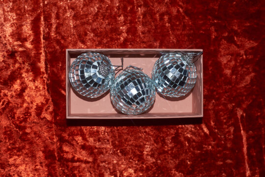 Shiny ornaments stored in a box on a plush red background