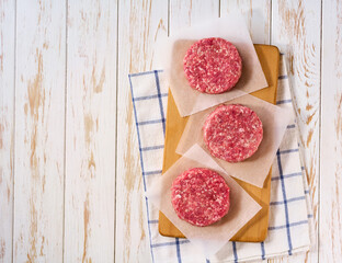 Raw burger beef patties on a white table, top view.
