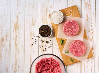 homemade burger beef patties on a white wooden table , top view.