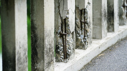 Weathered concrete fence with moss and stains along an asphalt walkway, showing age, decay, and urban texture in an outdoor environment.